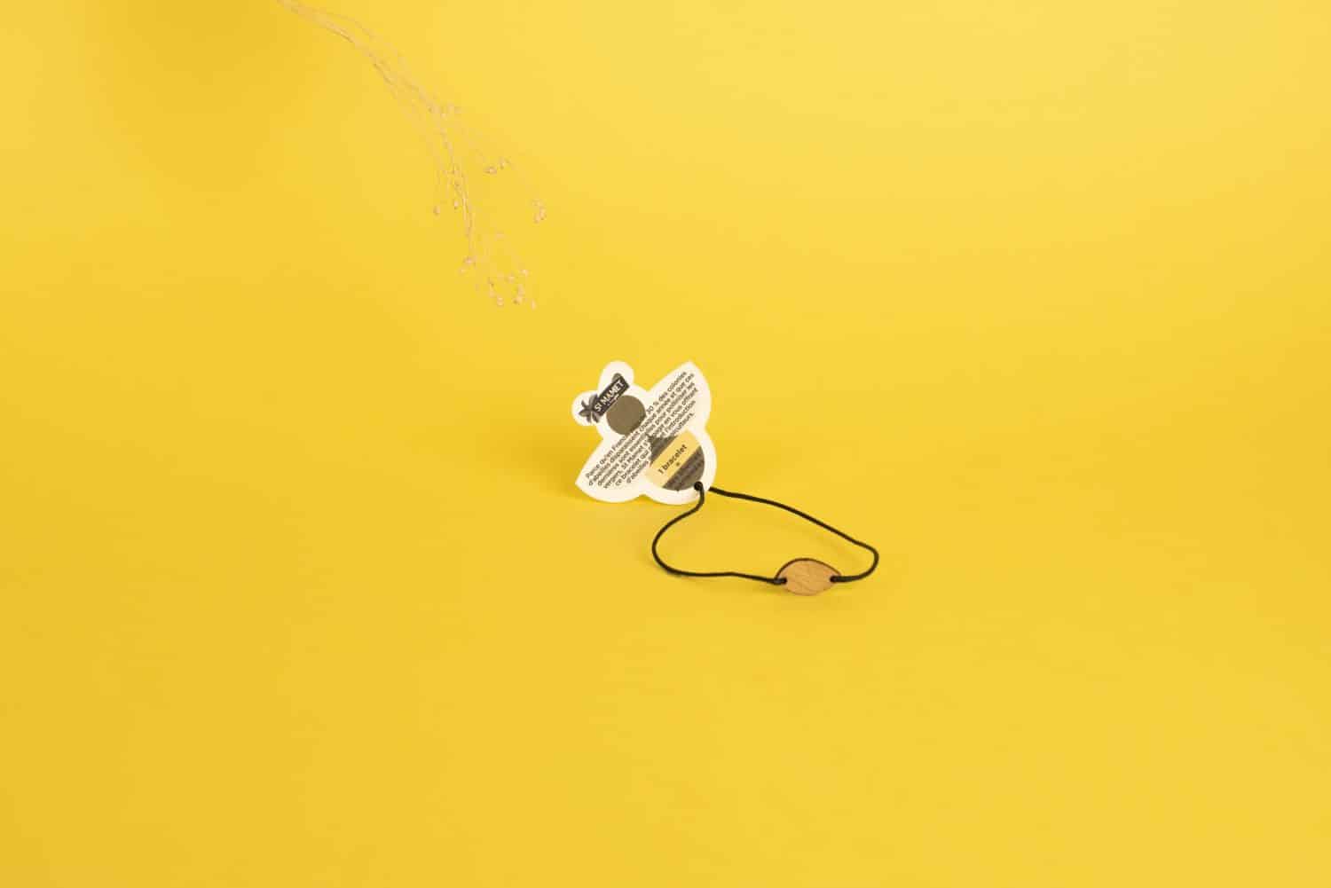 Un bracelet personnalisé mini en bois personnalisable et français avec une abeille dessus sur fond jaune.