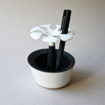 Un pot de crayons en forme de fleurs biodégradable et français rempli de fleurs, avec un stylo dedans.