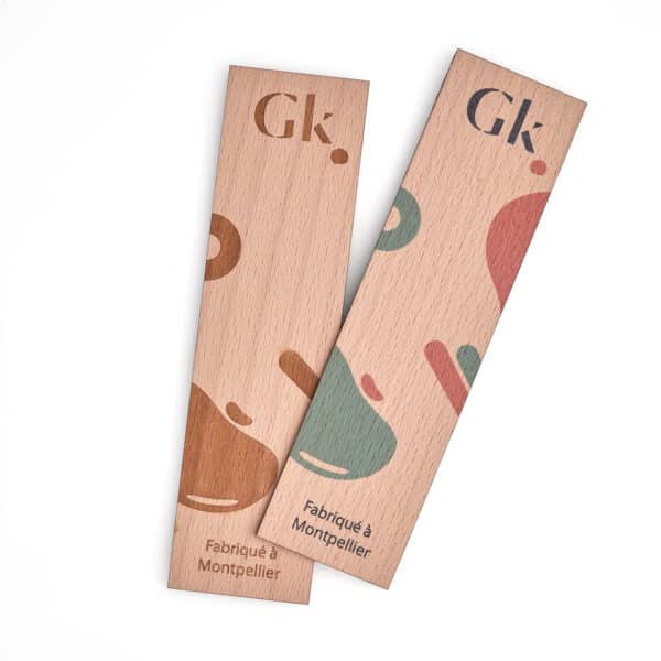 Deux Jeton de caddy écolo et personnalisable fabriqués en France en bois avec le mot gk dessus, comportant une languette.