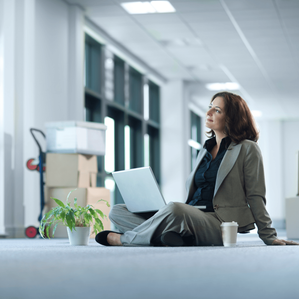 Une femme assise par terre avec un ordinateur portable dans un bureau écologique.