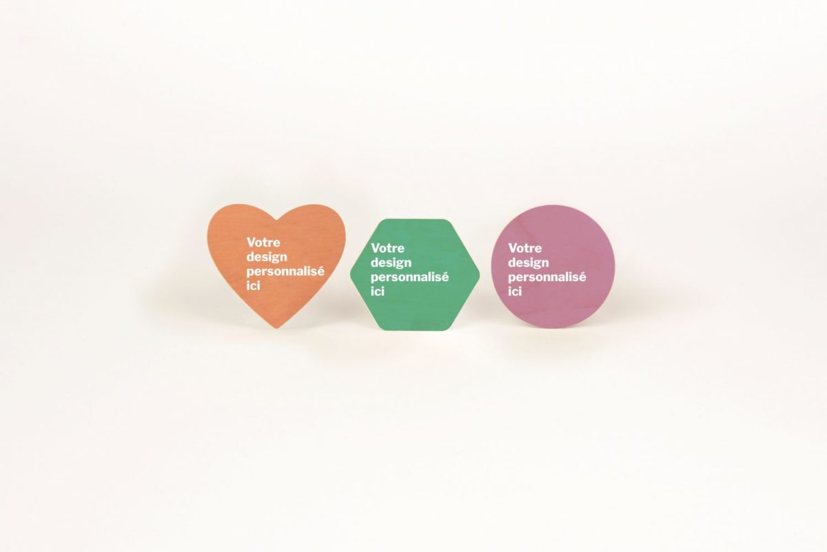 Trois stickers en bois personnalisables et français en forme de coeur sur une surface blanche.