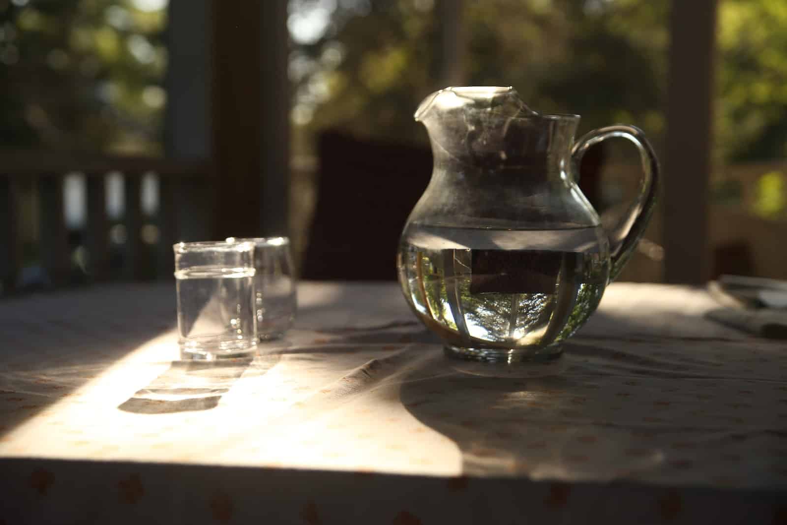 carafe d'eau en verre recyclé avec poignée sur une table