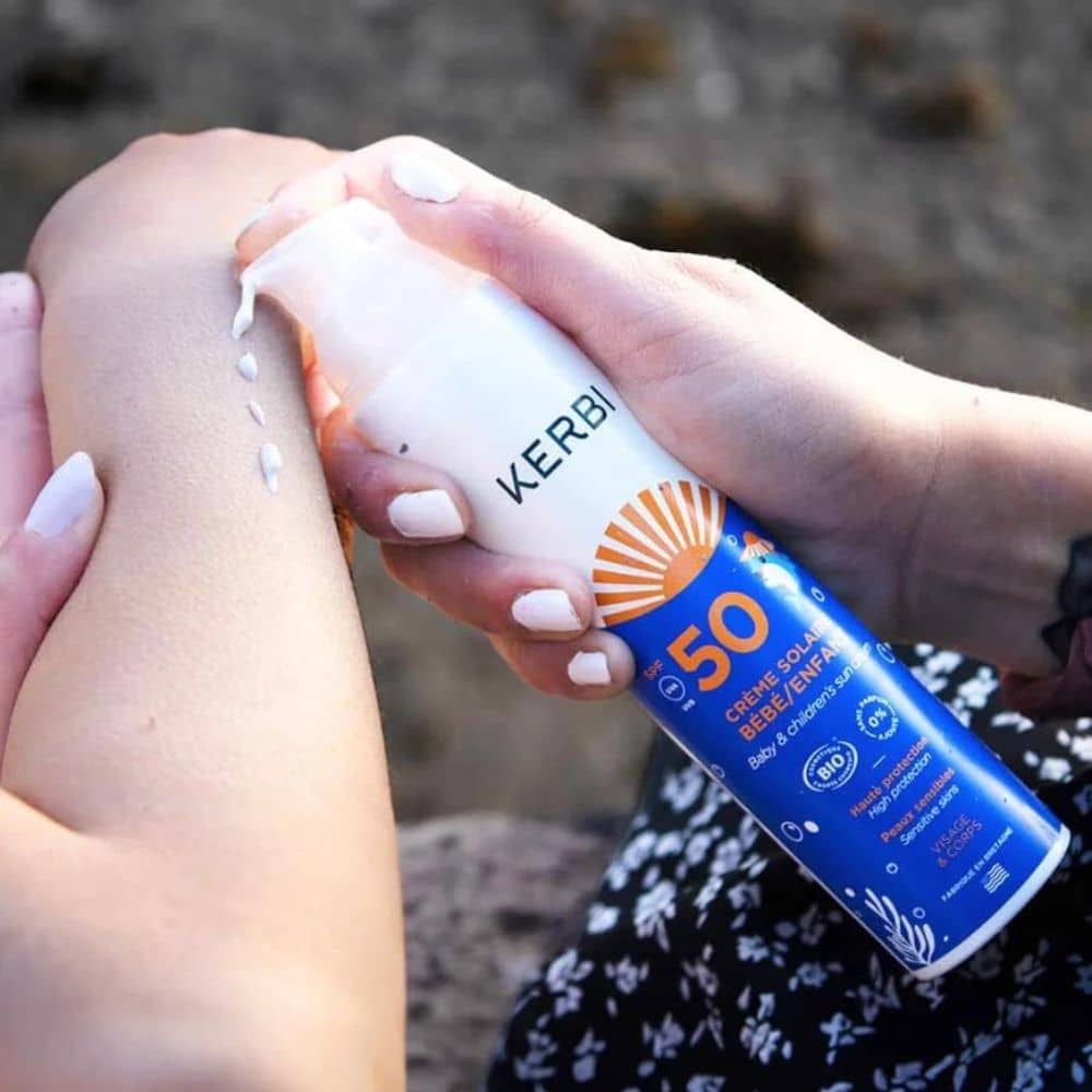 Une femme applique la Crème Solaire Bio Bébé & Enfant - crème solaire SPF50 sur son bras.